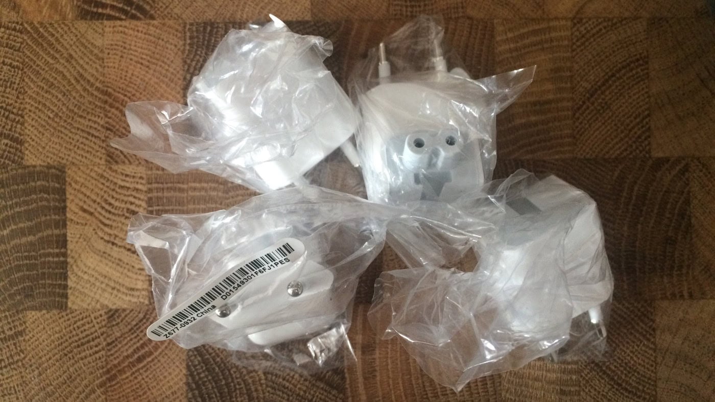 Vier verpackte weiße Steckdosenadapter auf Holzoberfläche