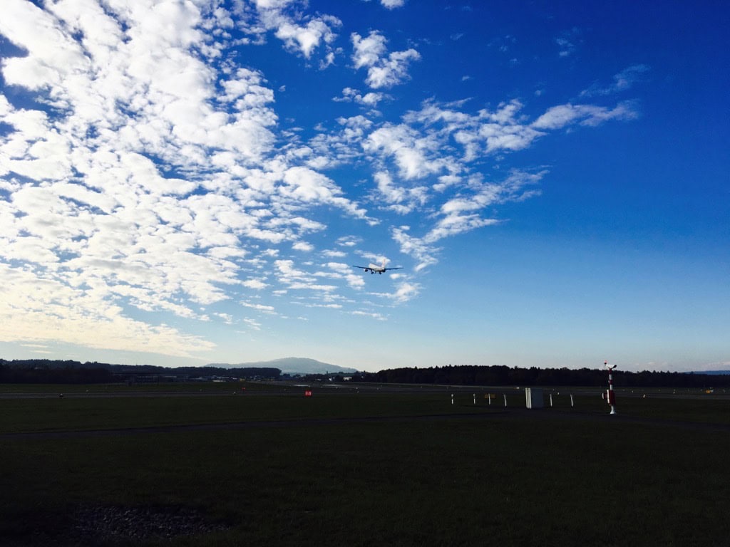 Flugzeug im Landeanflug über Start- und Landebahn bei Wolkenhimmel