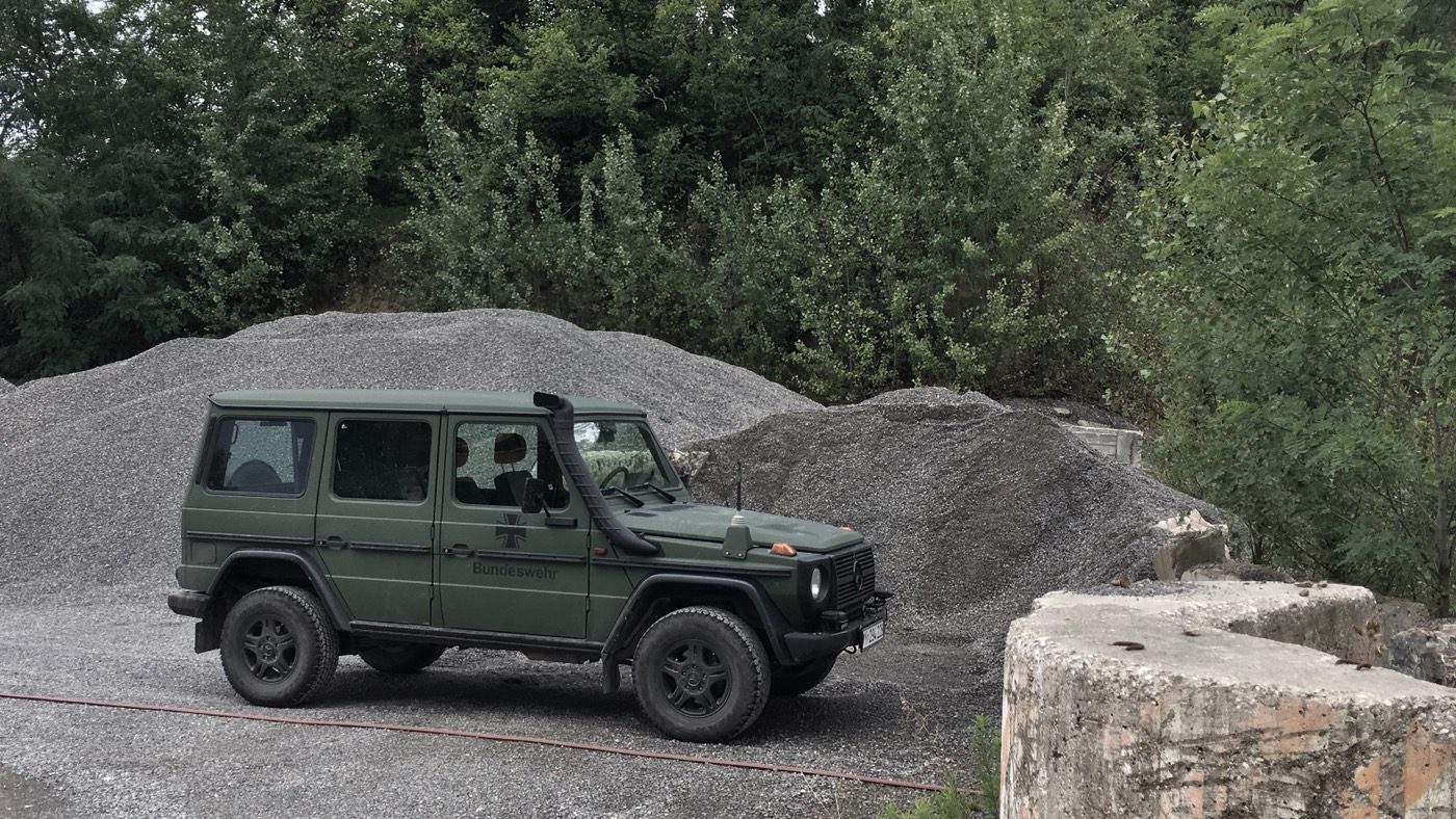 Militärischer Geländewagen der Bundeswehr vor Kieshaufen