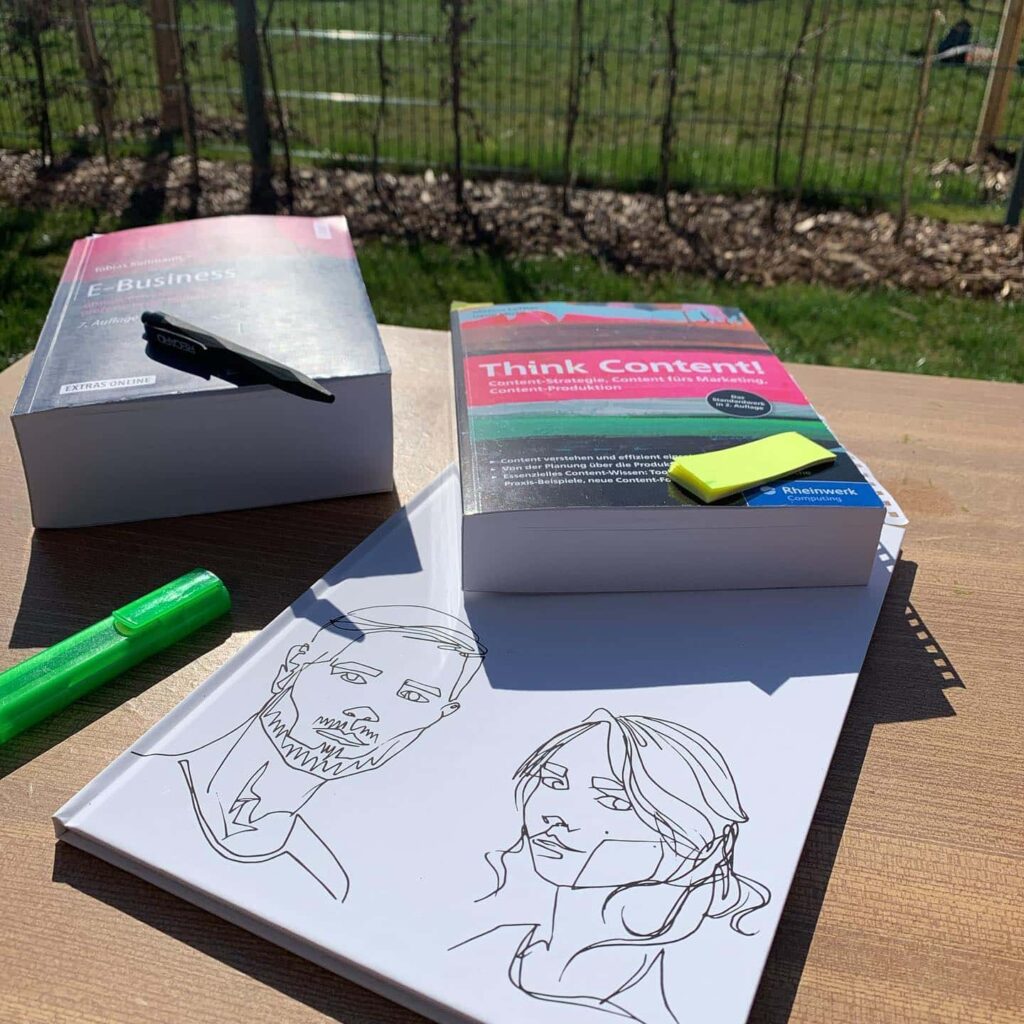 Bücher und Zeichnungen auf einem Tisch im Freien.