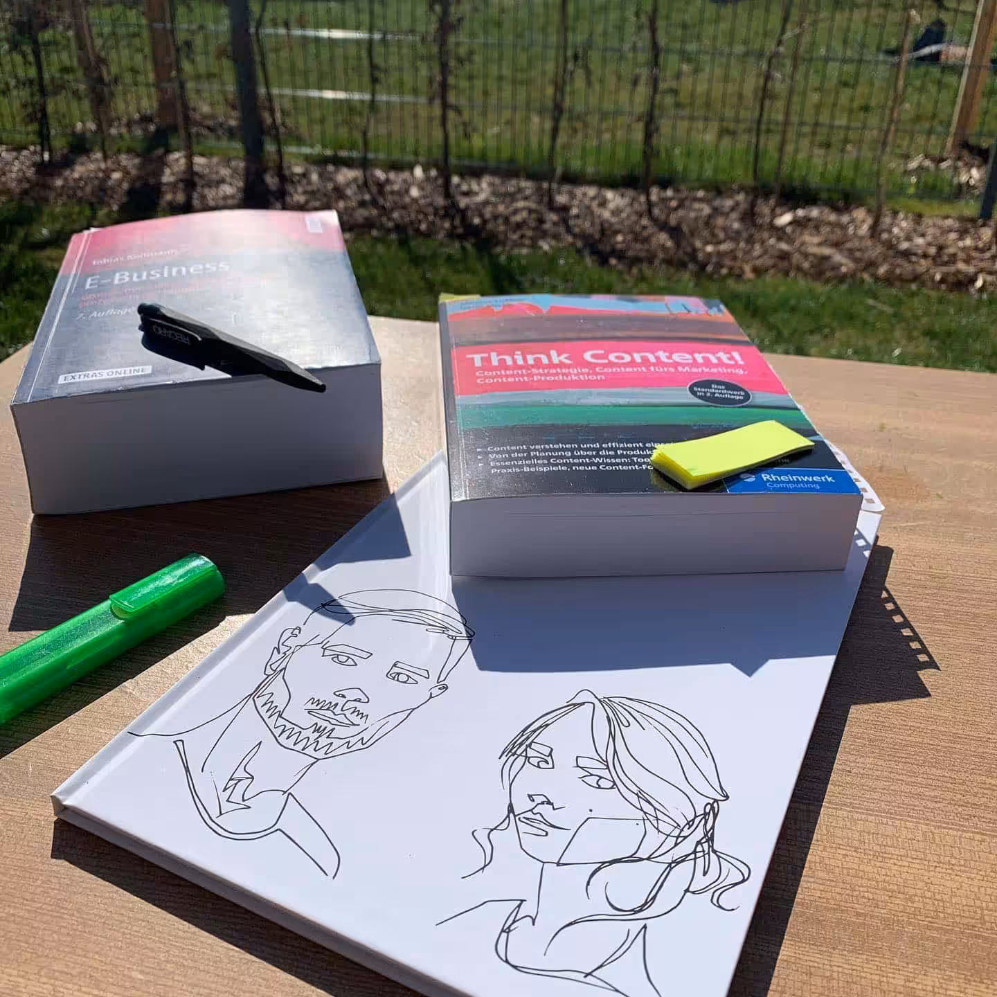 Bücher und Zeichnungen auf einem Tisch im Freien.