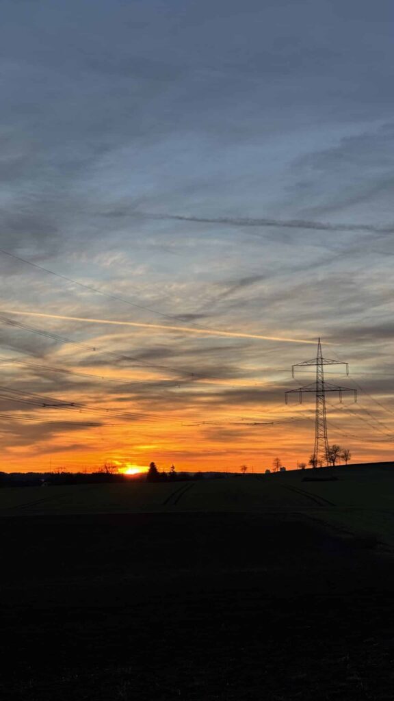 Sonnenuntergang mit Strommast und Wolken