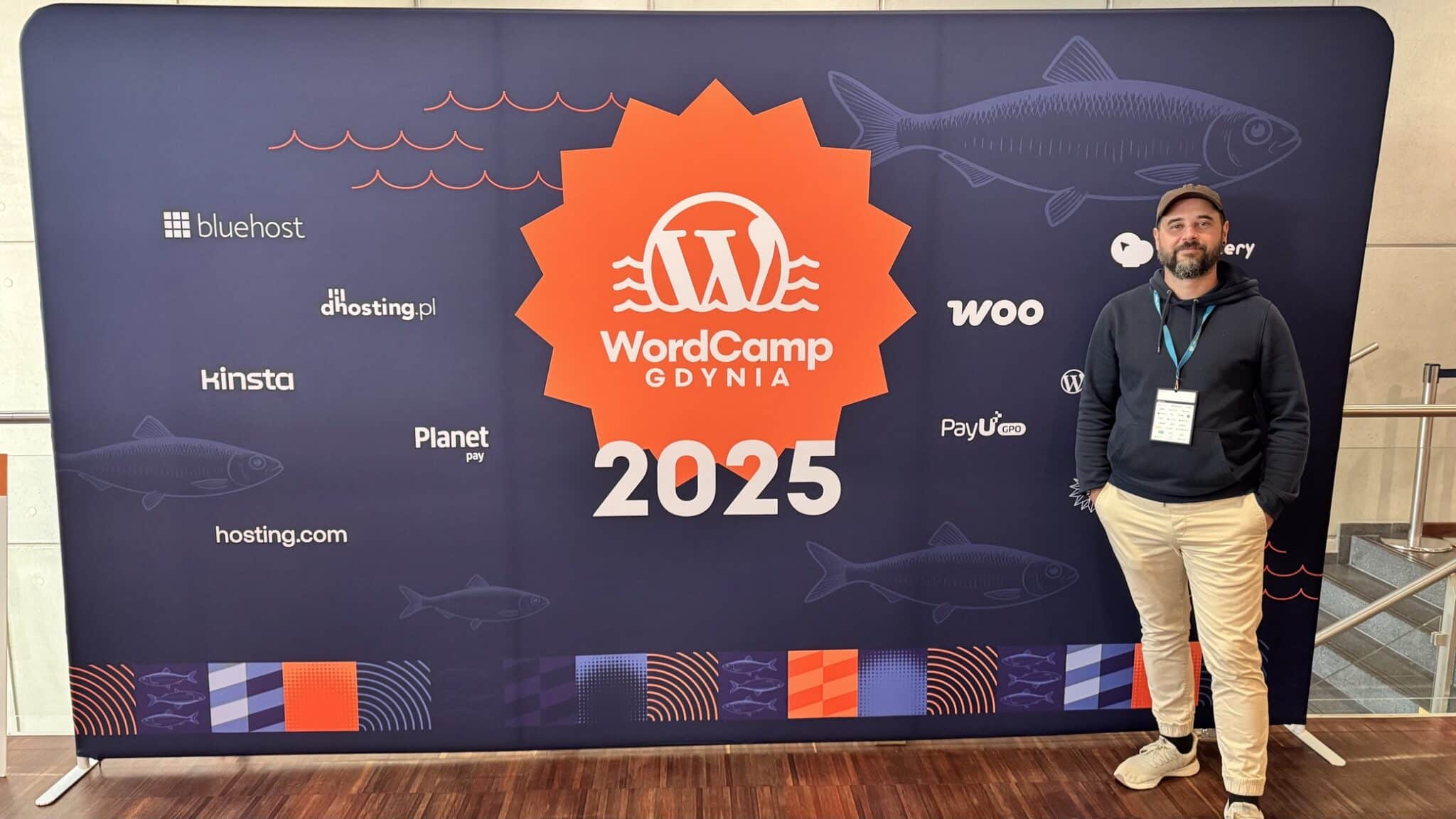 Christopher Kurth vor der Sponsoren-Wand für das WordCamp Gdynia 2025